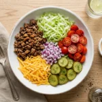 Big mac salad bowl with seasoned beef, cheddar, pickles, tomatoes, and special sauce on a white ceramic plate