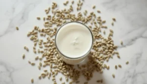 Hemp Milk Recipe hemp milk recipe in a tall glass surrounded by hemp seeds on a marble surface