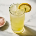 Homemade electrolyte drink recipe served in a tall glass with lemon slice and pink Himalayan salt on a marble surface