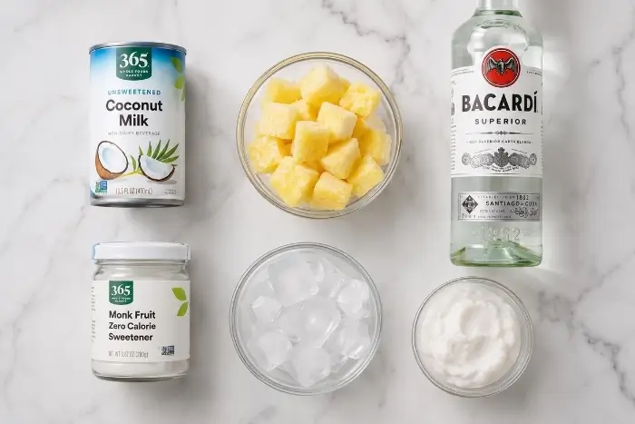 Ingredients for a skinny pina colada including coconut milk, frozen pineapple, rum, and monk fruit sweetener

