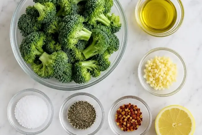 Roasted Broccoli 2 Flat lay of ingredients for roasted broccoli recipe including broccoli florets, olive oil, garlic, and lemon