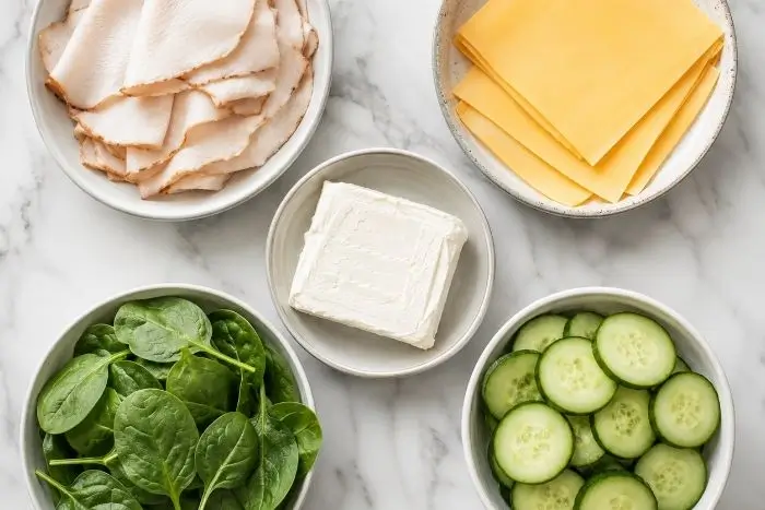 Fresh ingredients for turkey and cheese roll up including turkey, cheese, and spinach