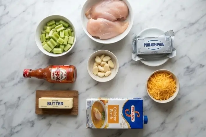 Ingredients for buffalo chicken soup including chicken, cream cheese, hot sauce, cheddar, and celery